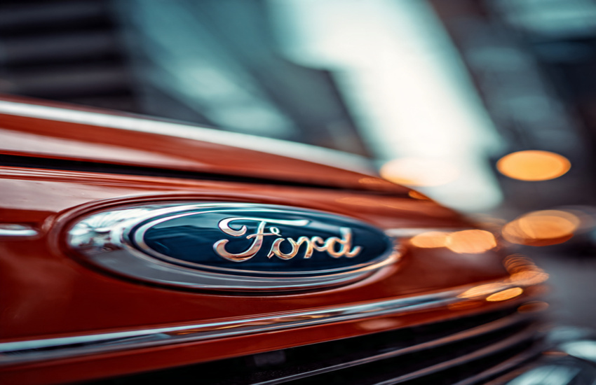 Close-up of Ford logo on a red vehicle with blurred city lights in the background